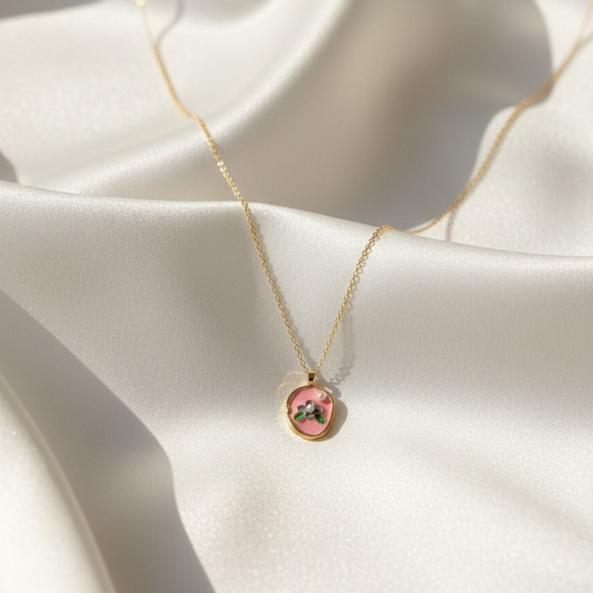 Gold necklace with a pink pendant on a white fabric background