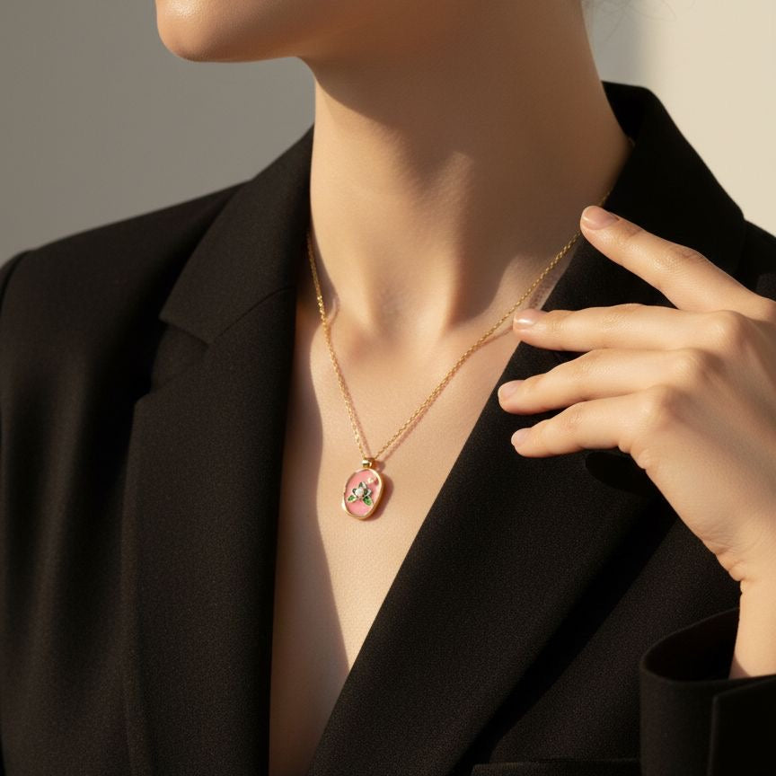 Person wearing a gold necklace with a pendant, touching their chin.