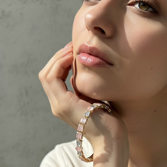 Close-up of a person wearing a pink beaded bracelet on a neutral background