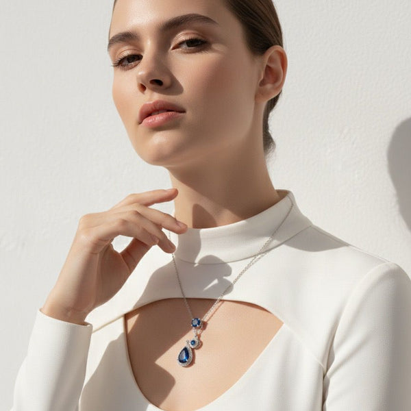 Woman wearing a necklace with a blue pendant against a white background