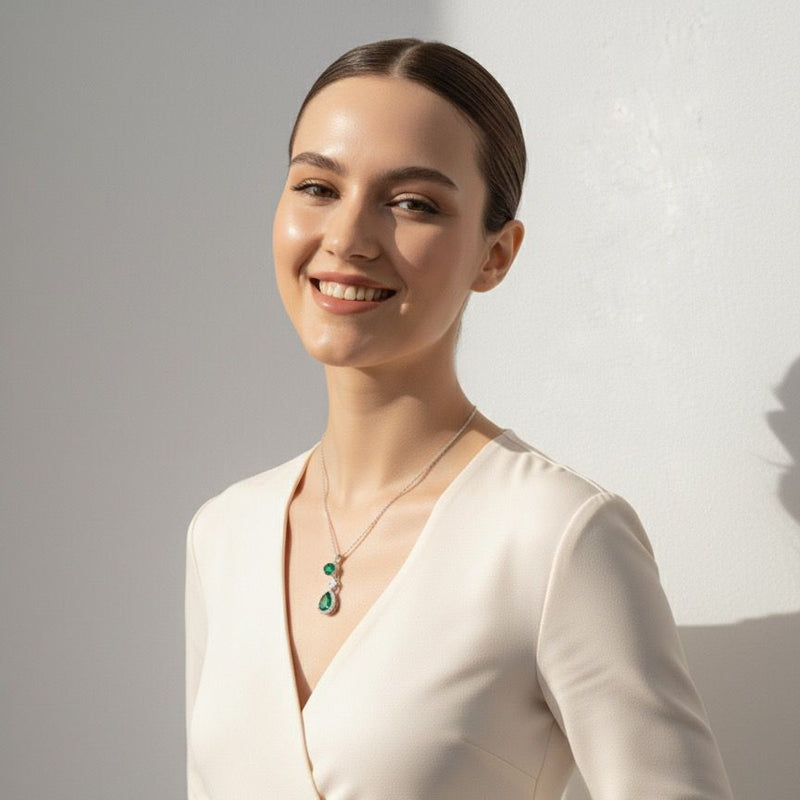 Woman wearing a white dress and green necklace against a plain background