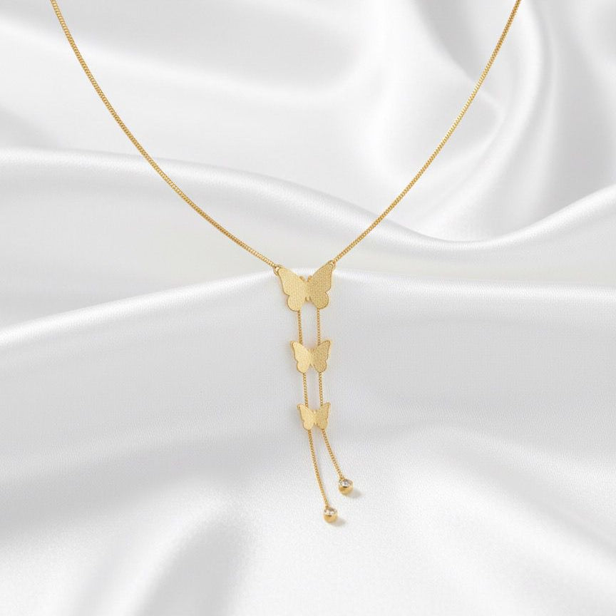 Gold butterfly necklace on a white satin background