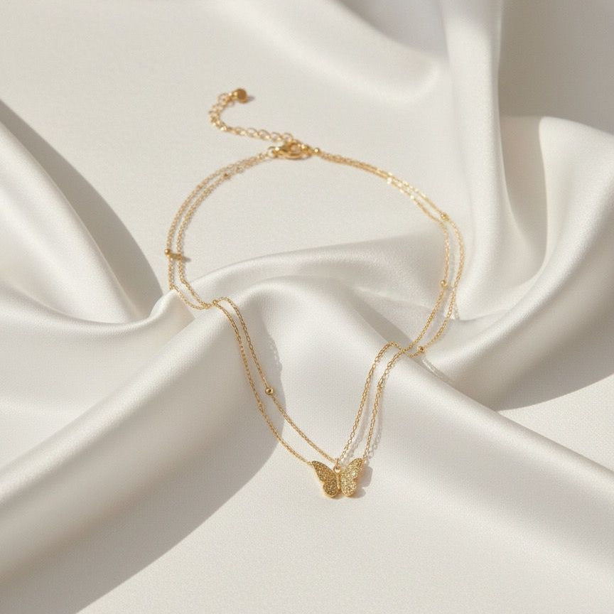 Gold bracelet with butterfly charm on a white fabric background