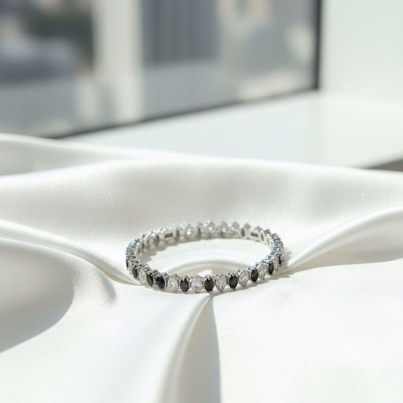 Silver ring with black stones on a white fabric surface