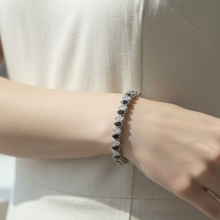 Close-up of a person wearing a bracelet with black and white stones on a light background