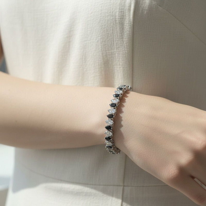 Close-up of a person wearing a bracelet with black and white stones on a light background