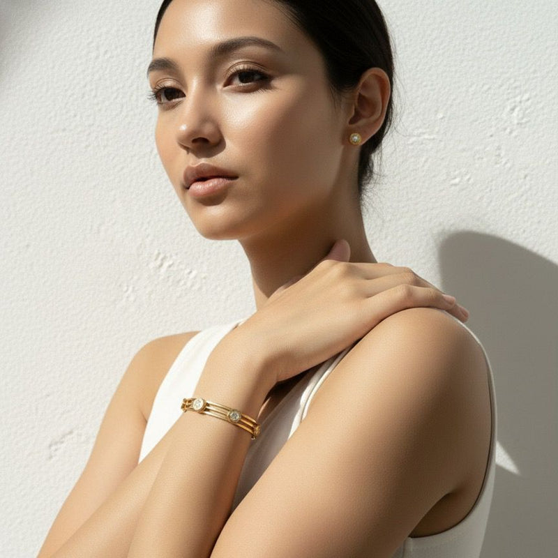 Woman wearing a gold bracelet against a white background