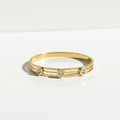 Gold ring with small diamonds on a light gray background