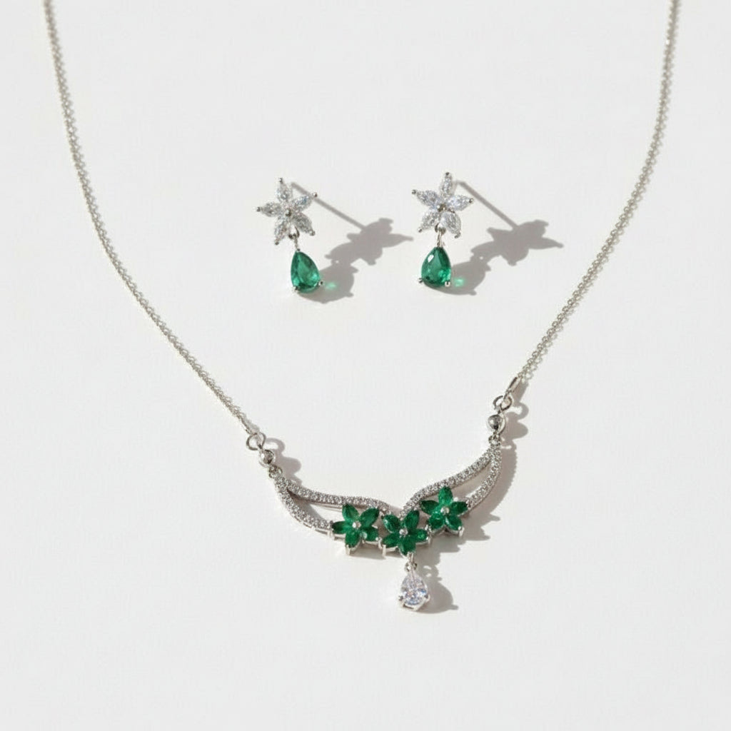 Jewelry set with necklace and earrings featuring green gemstones on a white background