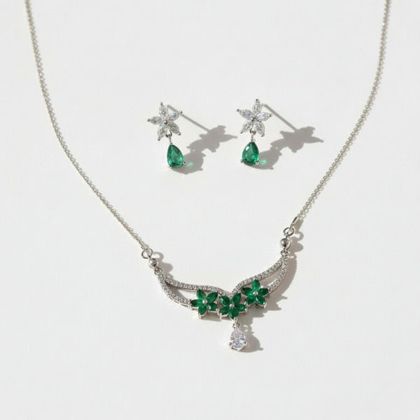 Jewelry set with necklace and earrings featuring green gemstones on a white background