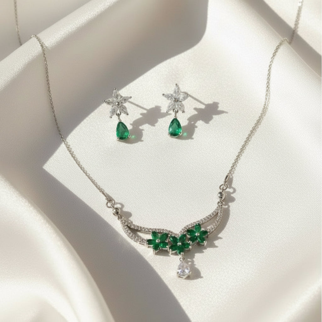 Jewelry set with necklace and earrings featuring green gemstones on a white surface