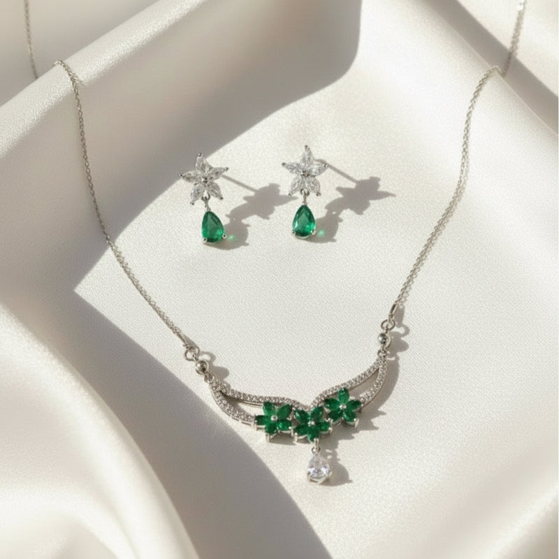 Jewelry set with necklace and earrings featuring green gemstones on a white surface