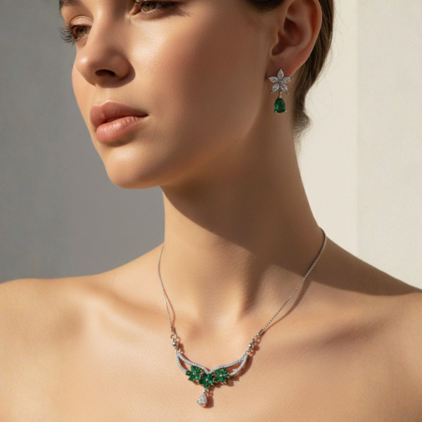 Woman wearing a necklace and earrings with green gemstones on a neutral background