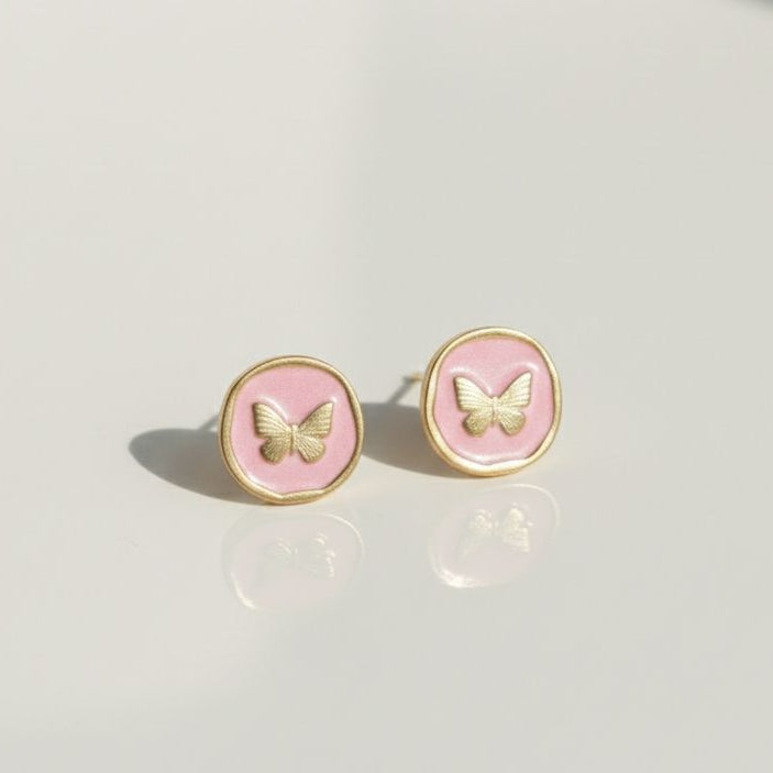 Pair of pink butterfly earrings on a light gray background