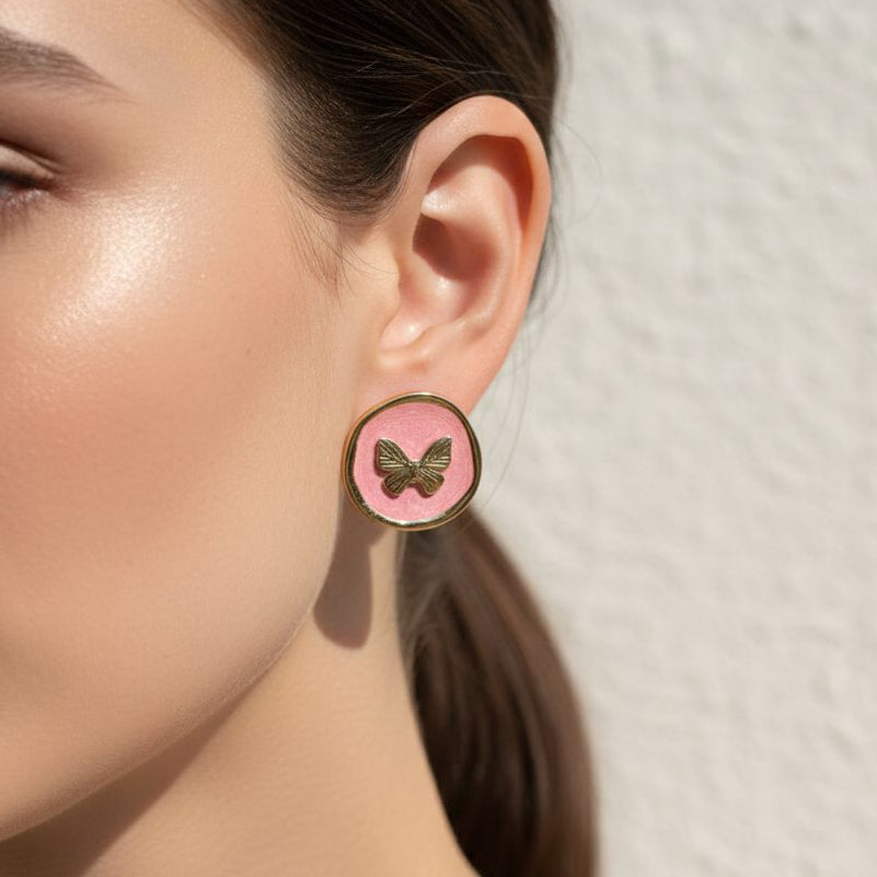 Close-up of a woman wearing a pink earring with a butterfly design against a neutral background