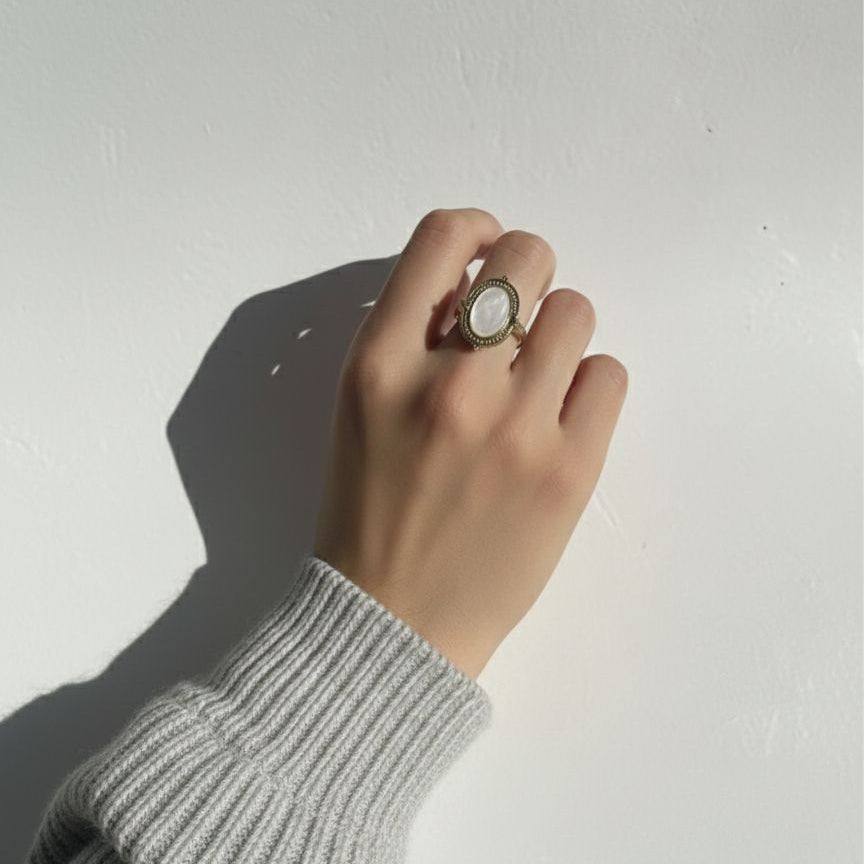 Hand wearing a ring on a plain background