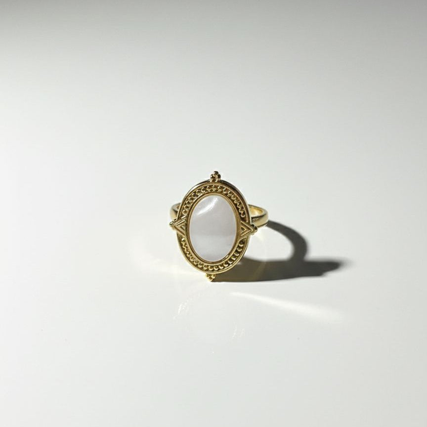 Gold ring with a central oval stone on a white background