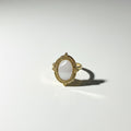 Gold ring with a central oval stone on a white background