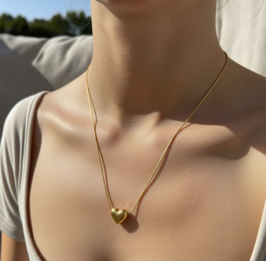 Gold necklace with a heart-shaped pendant on a person's neck
