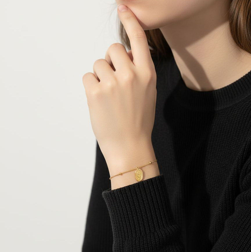 Woman wearing a gold bracelet on a plain background