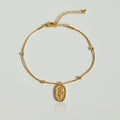 Gold bracelet with a floral charm on a light gray background