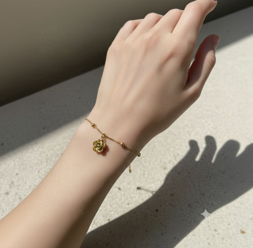 Hand wearing a gold bracelet with a decorative clasp on a neutral background