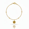 Gold bracelet with a floral charm on a white background
