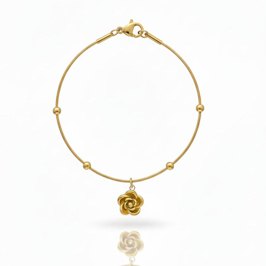 Gold bracelet with a floral charm on a white background