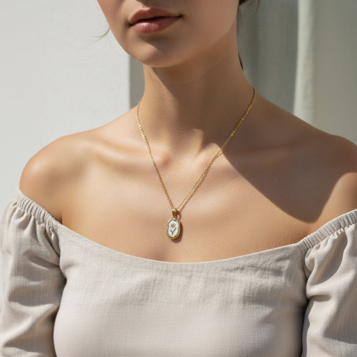 Woman wearing a gold necklace with a pendant against a neutral background