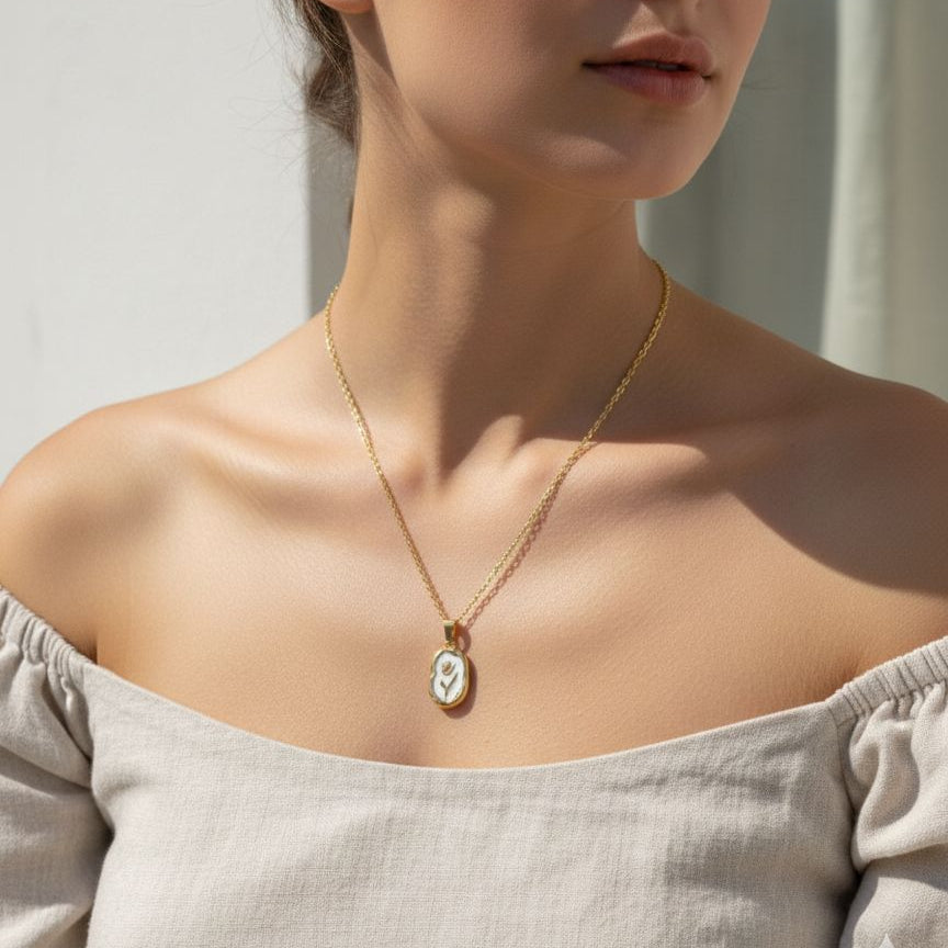 Woman wearing a gold necklace with a pendant against a neutral background