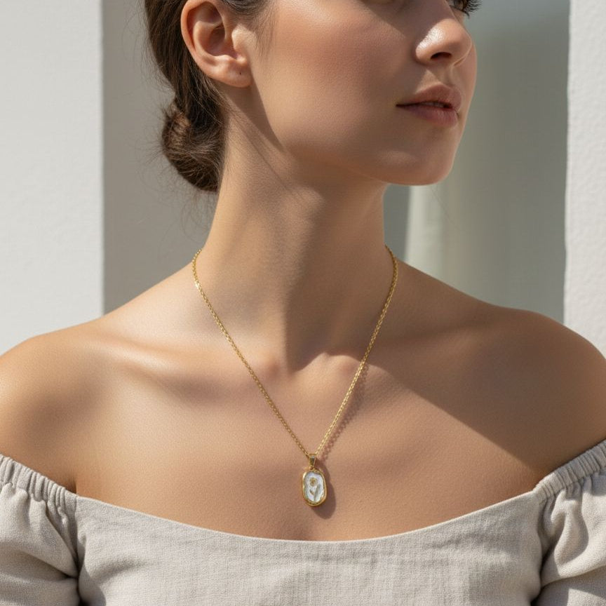 Woman wearing a gold necklace with a pendant against a neutral background