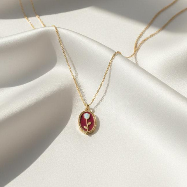 Gold necklace with a red pendant on a white fabric background