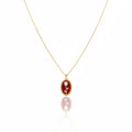 Gold necklace with a red pendant on a white background
