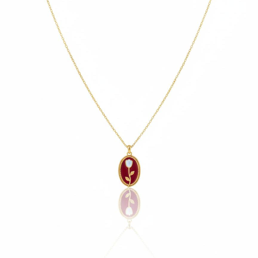 Gold necklace with a red pendant on a white background