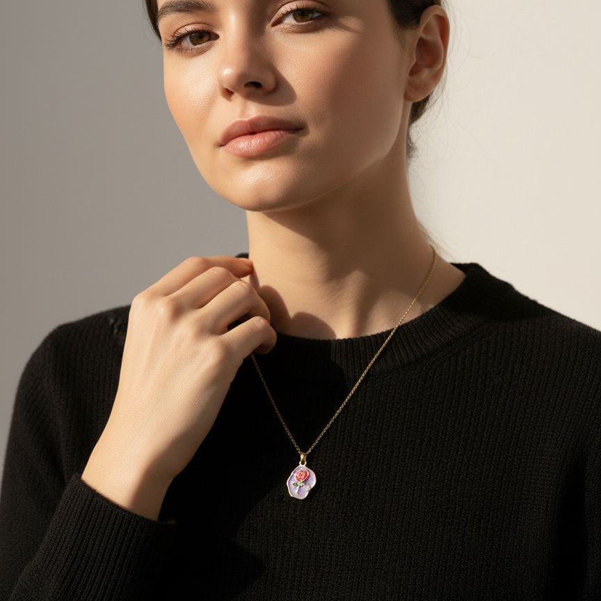 Woman wearing a black sweater and a necklace with a pendant against a neutral background