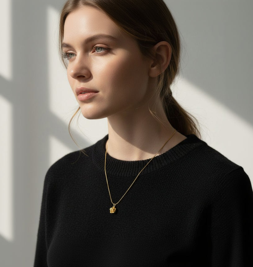 Woman wearing a gold necklace against a neutral background