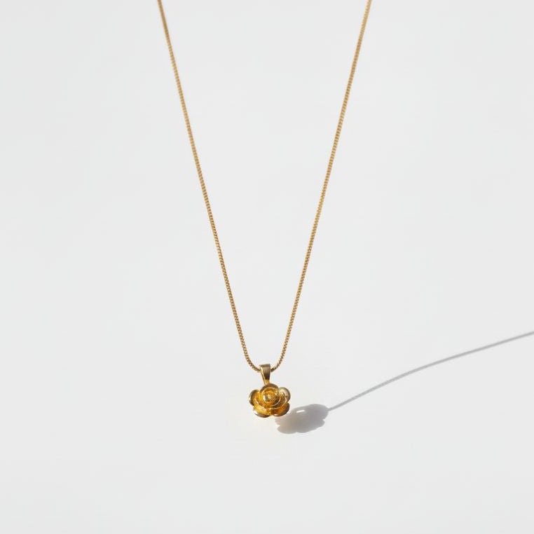 Gold necklace with a small pendant on a white background