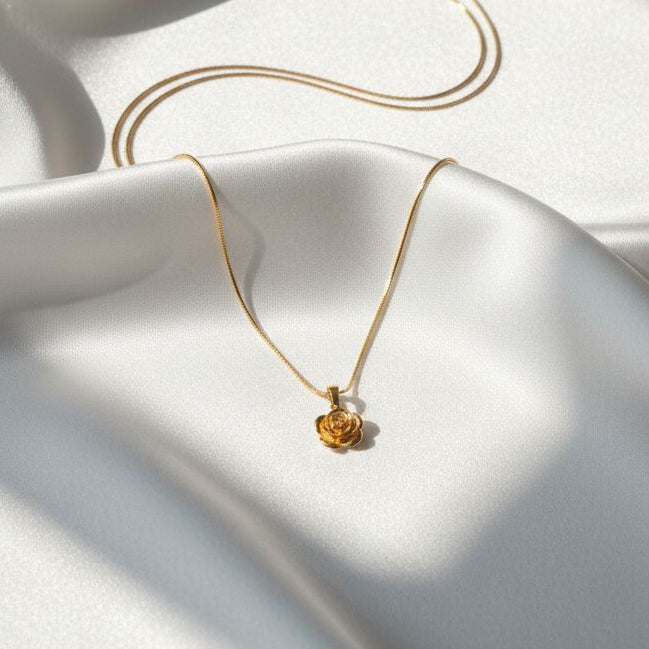 Gold necklace with a small pendant on a white fabric background