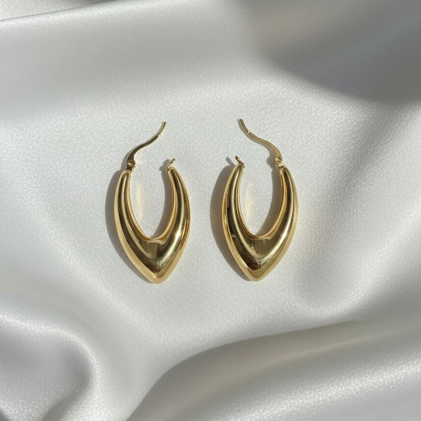 Gold hoop earrings on a white fabric background