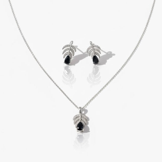 Silver necklace and earrings with black stones on a white background